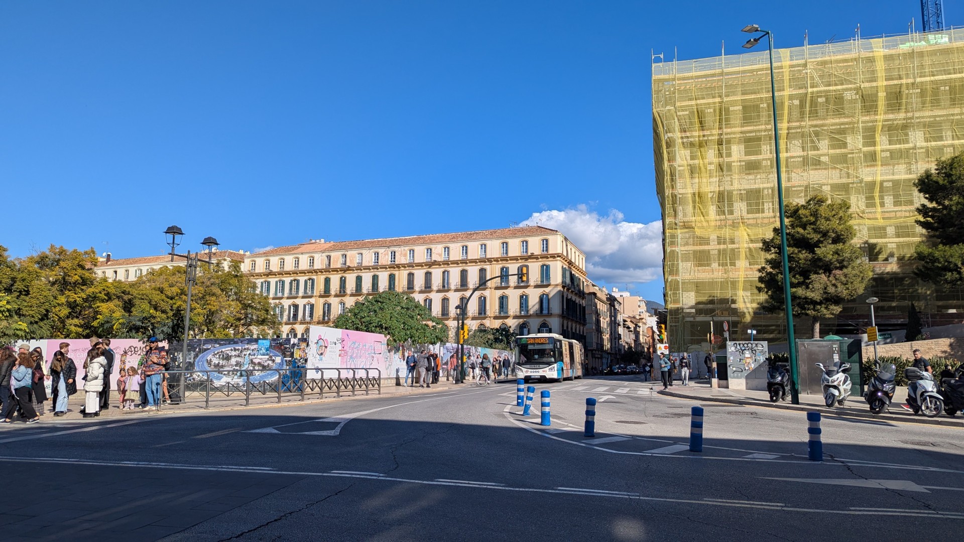 En la foto se puede apreciar a la derecha un edificio en construcción con un andamio amarillo, al fondo algo más bajas unas casas históricas de 4 alturas del siglo XIX, y en el centro de la imagen, pero algo alejado del punto de vista, un autobús urbano de línea. El cielo es predominante en la foto y es azul intenso.