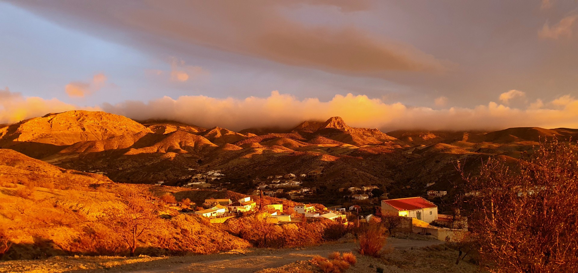 Landscape view of mountains just after sunrise. The mountains have a golden glow and low clouds covering the tops.
Vista del paisaje de montañas justo después del amanecer. Las montañas tienen un resplandor dorado y nubes bajas cubren las cumbres.